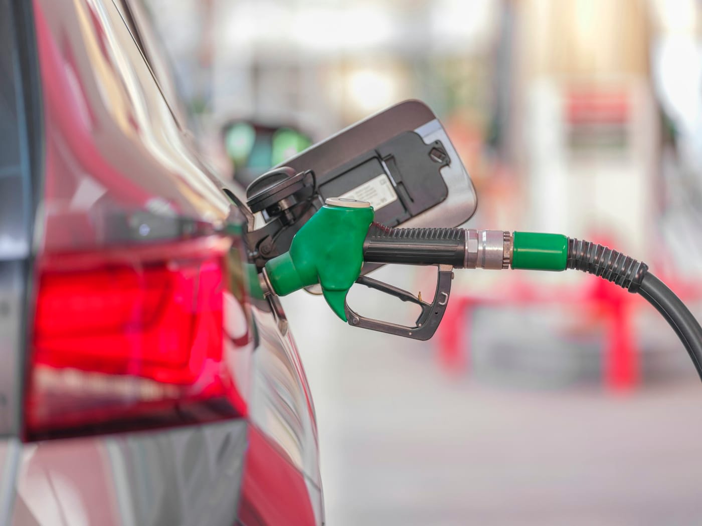 A fuel nozzle in a vehicle's filler neck at a station forecourt.